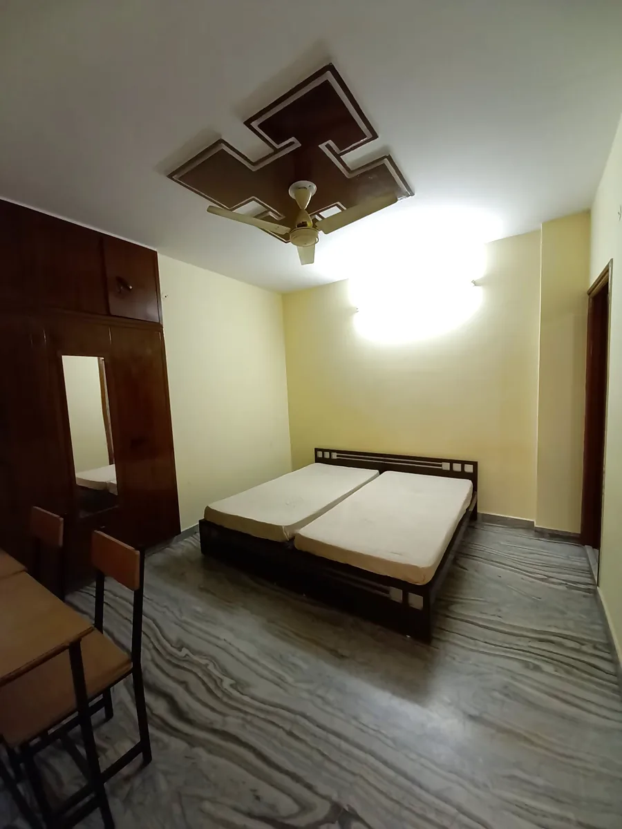 Furnished deluxe room with double bed, wardrobe and study table